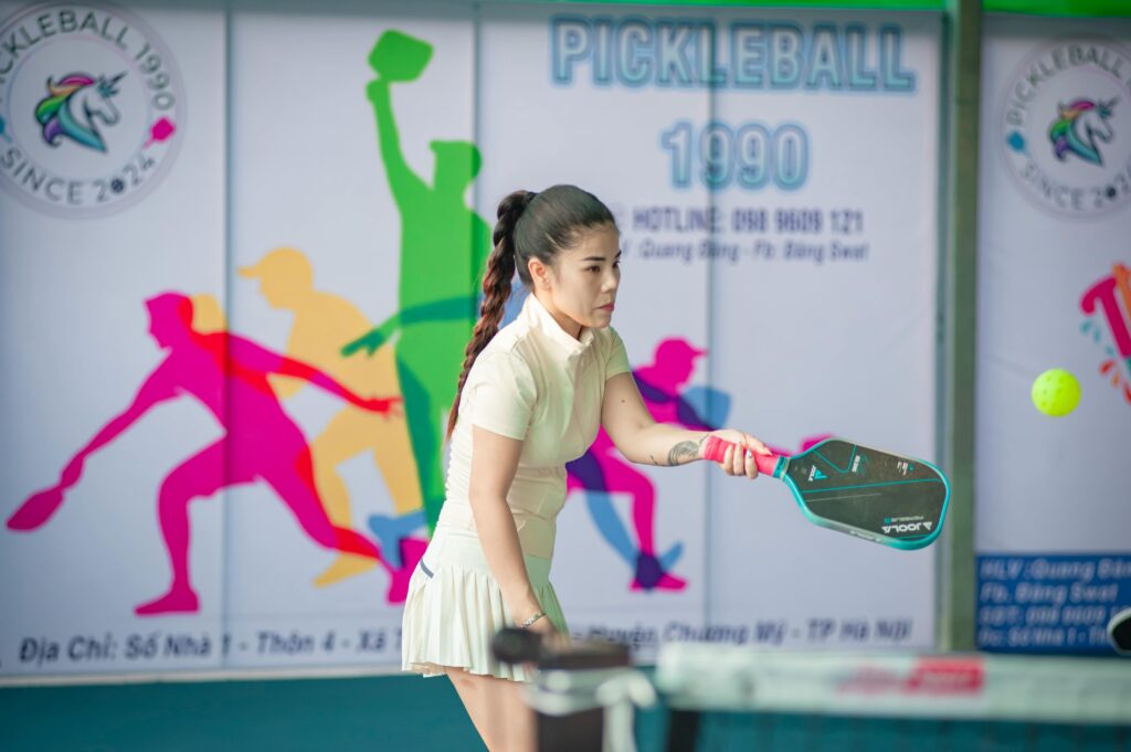 Woman actively engaged in a game of pickleball indoors in Hanoi, Vietnam.