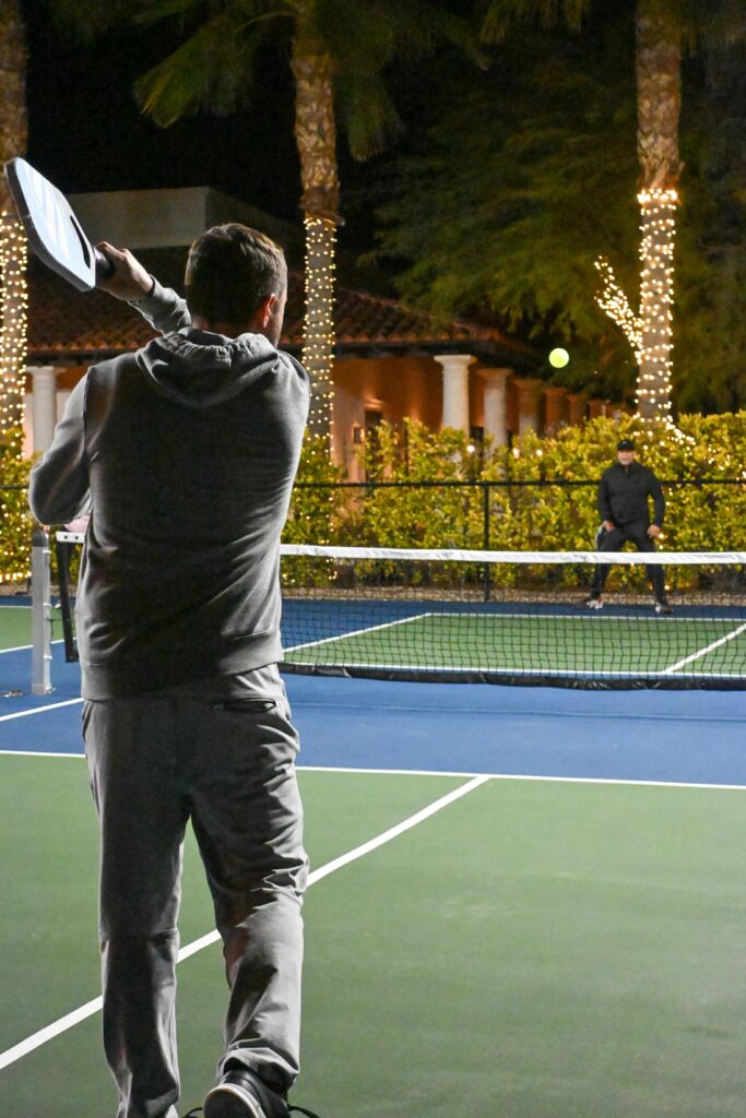 Engaging pickleball match under lit palm trees at night in Scottsdale.